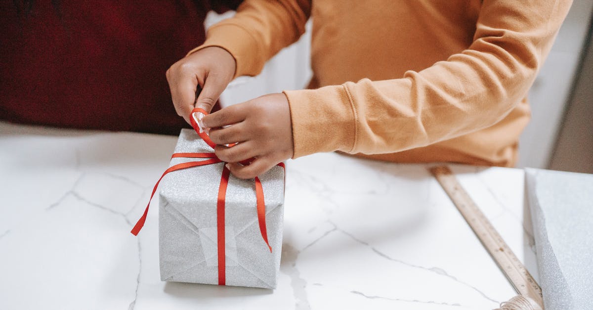 Processing time of a working holiday visa in New Zealand - Crop ethnic child tying ribbon on gift box at home Processing time of a working holiday visa in New Zealand - Crop ethnic child tying ribbon on gift box at home
