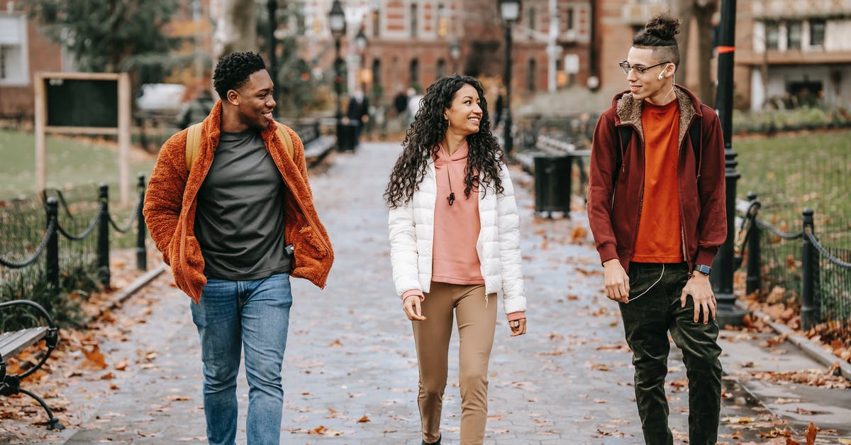 Proof of earnings - what to do if I am a full time student? - Positive young ethnic guys with female friend walking along pathway in city Proof of earnings - what to do if I am a full time student? - Positive young ethnic guys with female friend walking along pathway in city