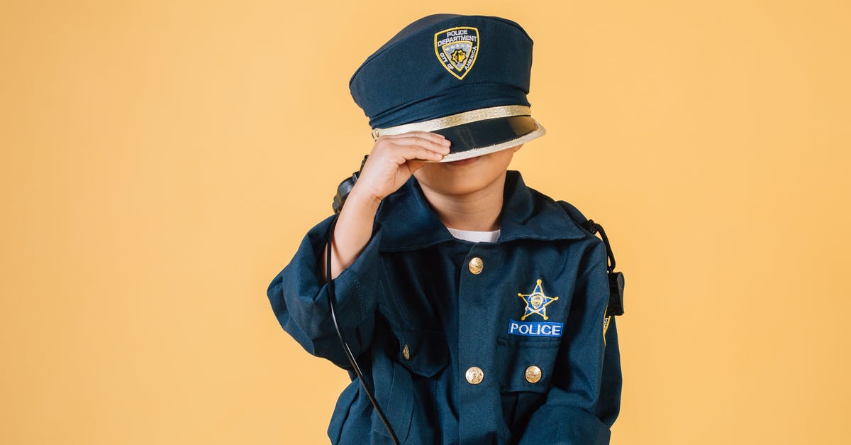 Purpose of the 'Witches' Hats' on the A13 in London - Unrecognizable child in police uniform standing in studio with transceiver in hand and pulling cap over face on yellow background Purpose of the 'Witches' Hats' on the A13 in London - Unrecognizable child in police uniform standing in studio with transceiver in hand and pulling cap over face on yellow background