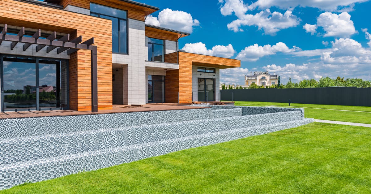 Queenstown, New Zealand private transfers - Exterior of contemporary residential house with panoramic windows glass doors and green lawn in yard on sunny day against blue sky with white clouds Queenstown, New Zealand private transfers - Exterior of contemporary residential house with panoramic windows glass doors and green lawn in yard on sunny day against blue sky with white clouds