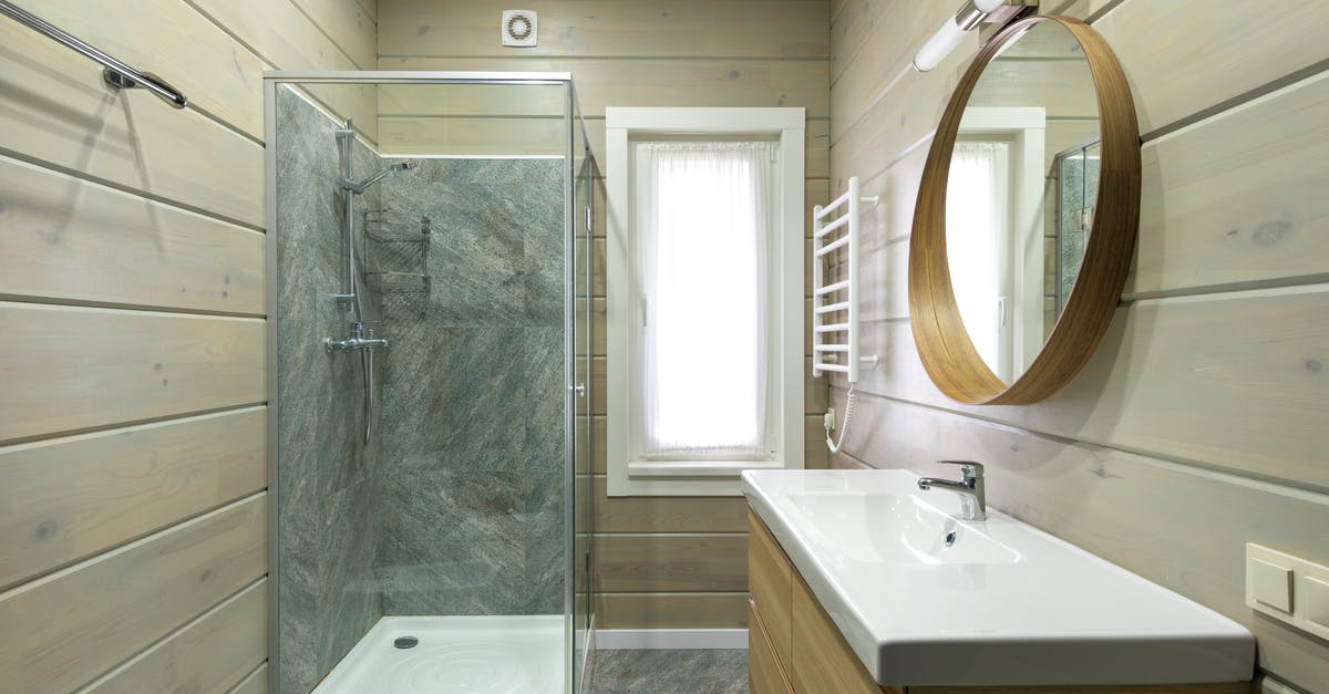 Queenstown, New Zealand private transfers - Contemporary bathroom design with round mirror hanging above sink and shower cabin near window and paneled walls Queenstown, New Zealand private transfers - Contemporary bathroom design with round mirror hanging above sink and shower cabin near window and paneled walls