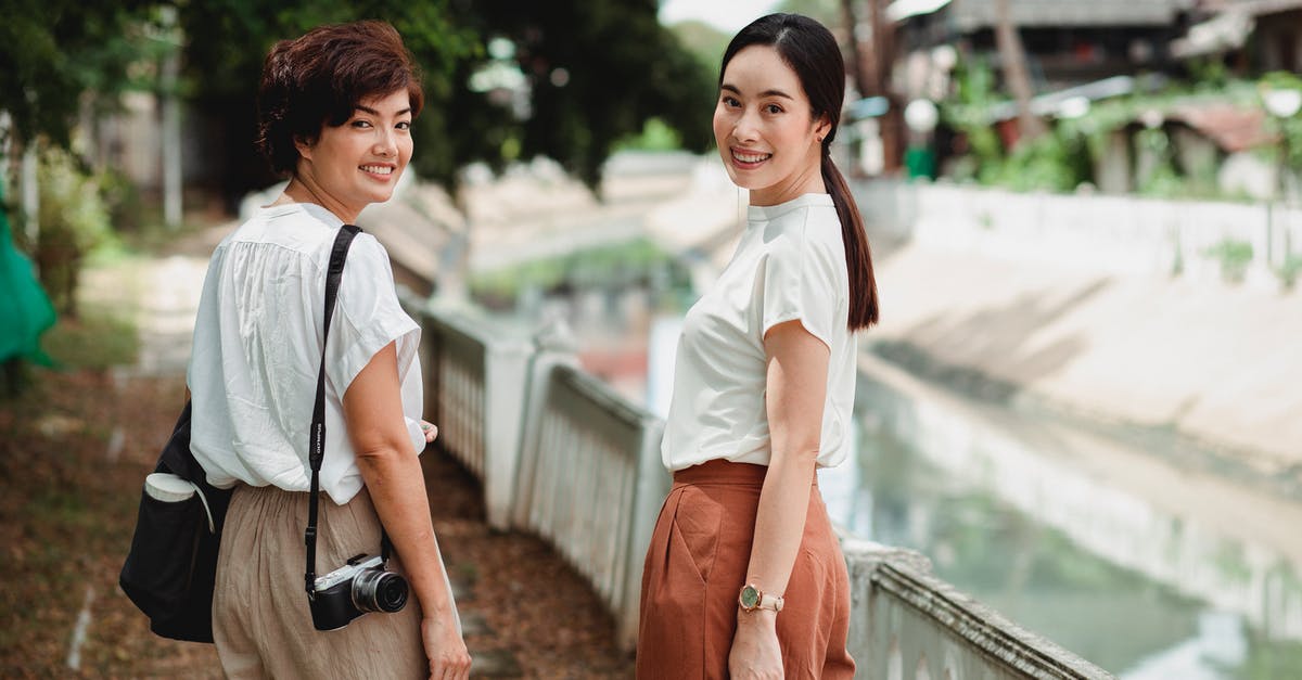 Re enter in UK over weekend ICT visa - Happy Asian women on urban embankment near canal
