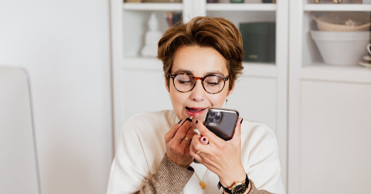 Re-applying after a refused visa application - Woman putting on lipstick using smartphone front camera Re-applying after a refused visa application - Woman putting on lipstick using smartphone front camera
