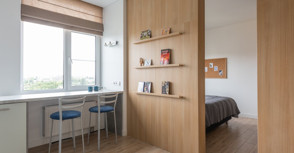 Regarding quota percentage in counter booking - Interior of light flat with counter near chairs and windows with jalousie near shelves with books and entrance in room with bed in daylight Regarding quota percentage in counter booking - Interior of light flat with counter near chairs and windows with jalousie near shelves with books and entrance in room with bed in daylight
