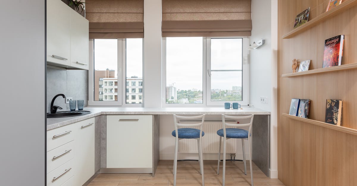 Regarding quota percentage in counter booking - Interior of light kitchen with counter with sink and faucet near chairs and windows with jalousie and wooden shelves with books Regarding quota percentage in counter booking - Interior of light kitchen with counter with sink and faucet near chairs and windows with jalousie and wooden shelves with books