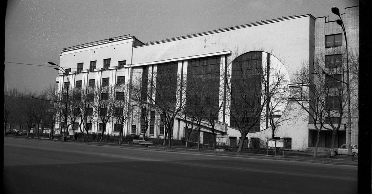 Registering with Federal Migration in Russia - Black and white of aged multistory garage building with symmetric windows located near empty asphalt road in Moscow Registering with Federal Migration in Russia - Black and white of aged multistory garage building with symmetric windows located near empty asphalt road in Moscow