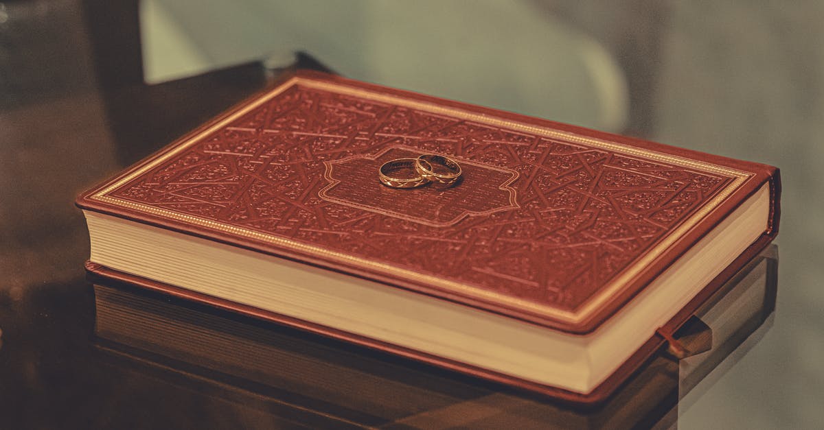 Religious wedding after civil wedding - Composition of golden rings placed on red ornamental book placed on glass table Religious wedding after civil wedding - Composition of golden rings placed on red ornamental book placed on glass table