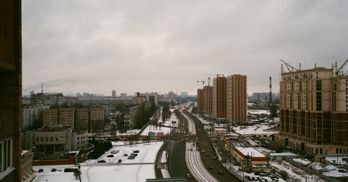 Renting a flat or rooms in the Alps area for winter season [closed] - Modern apartment city district with snowy streets and buildings under construction on gloomy overcast winter day