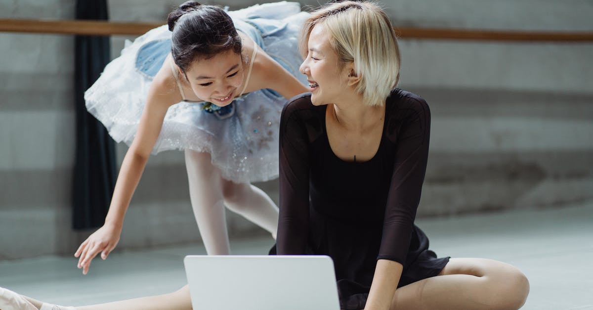 Renting personal laptop in Las Vegas? - Cheerful Asian ballerina in tutu skirt with personal trainer searching information in netbook while laughing together in ballet studio Renting personal laptop in Las Vegas? - Cheerful Asian ballerina in tutu skirt with personal trainer searching information in netbook while laughing together in ballet studio