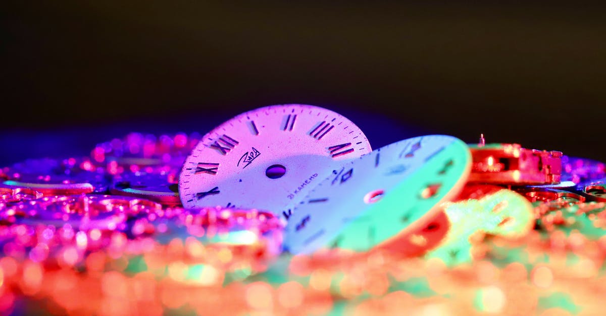 Reservation for multiple room in hotel - different check-in time - Round clock faces with Roman and Arabic numerals placed among stack of watch movements in dark room on black background Reservation for multiple room in hotel - different check-in time - Round clock faces with Roman and Arabic numerals placed among stack of watch movements in dark room on black background