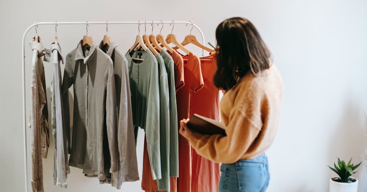 Reservation for multiple room in hotel - different check-in time - Faceless female seller with notepad near clothes on hangers Reservation for multiple room in hotel - different check-in time - Faceless female seller with notepad near clothes on hangers