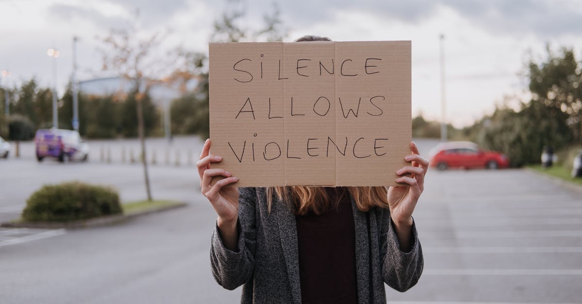 Reserved parking for women in Germany - Unrecognizable woman in casual clothes standing on road and demonstrating poster Silence Allows Violence Reserved parking for women in Germany - Unrecognizable woman in casual clothes standing on road and demonstrating poster Silence Allows Violence