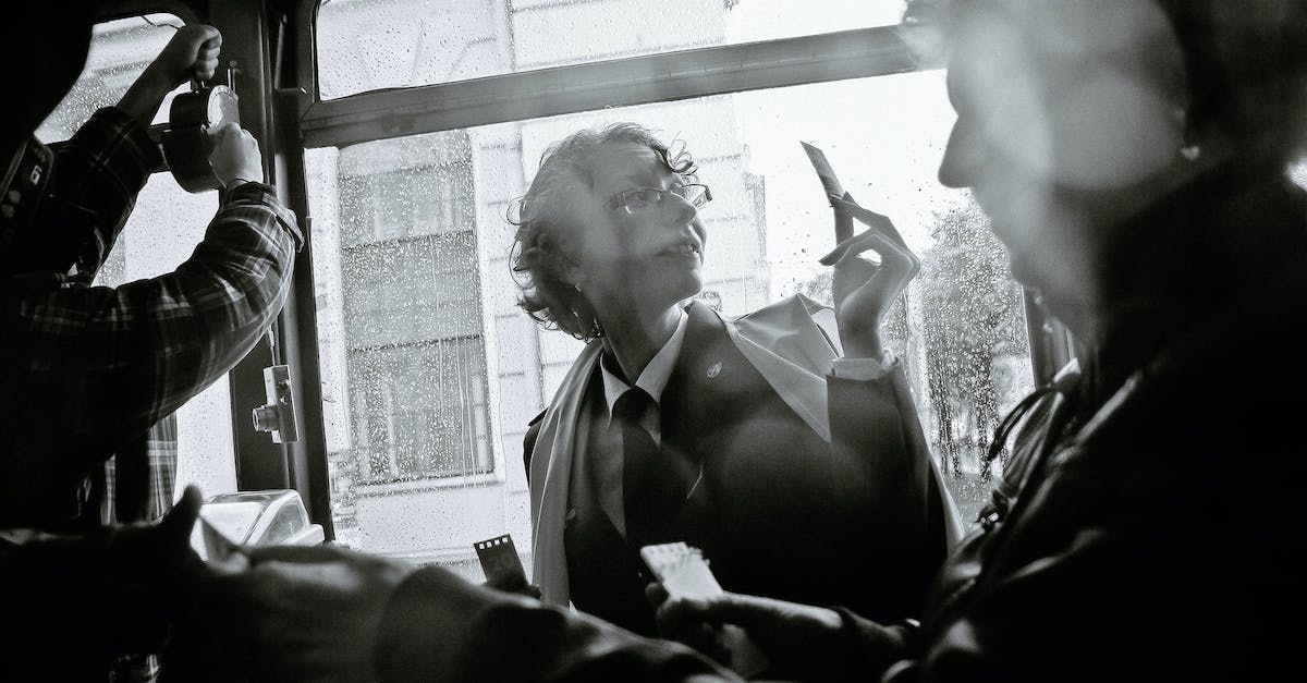 Return bus ticket from Bangalore to Goa? - Black and white of woman near crop male passenger using ticket puncher in retro vehicle during trip