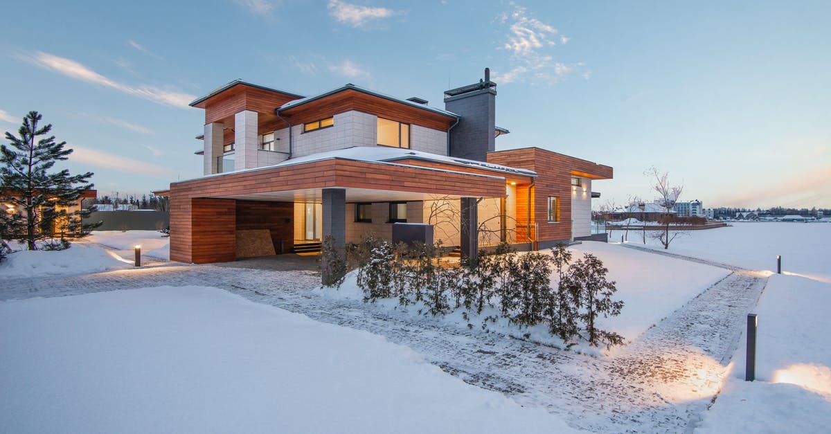 Return to my country without returning residence card - Exterior view of luxurious residential house with roofed parking and spacious backyard in snowy winter countryside