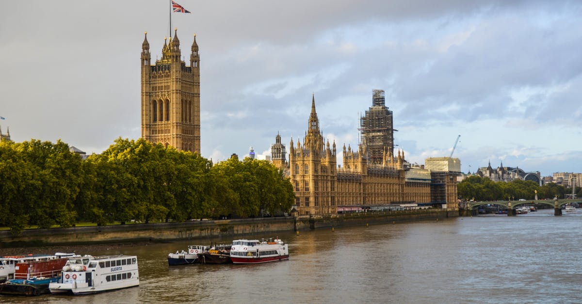 River Thames Source and Destination Points - Exterior of aged building of the Houses of Parliament on bushy coast near river with vessels under cloudy sky of London River Thames Source and Destination Points - Exterior of aged building of the Houses of Parliament on bushy coast near river with vessels under cloudy sky of London