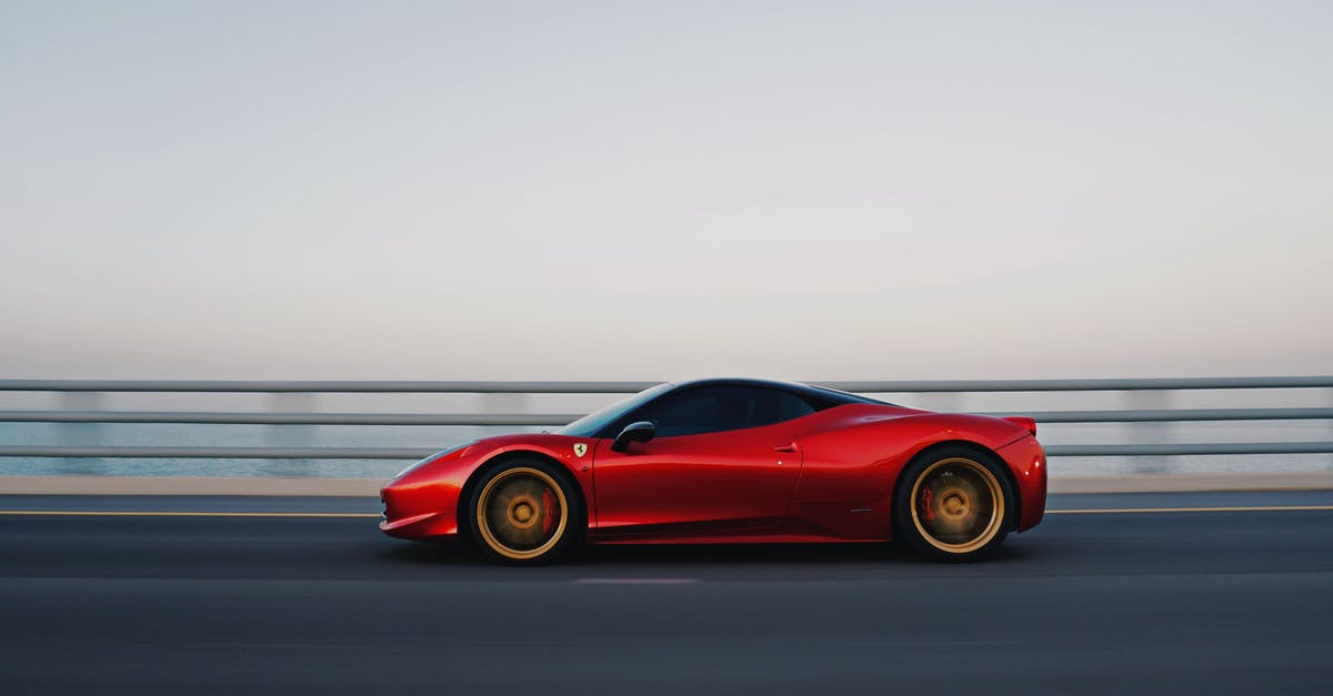 Roadtrip coast to coast in the USA, let someone else drive car back - Red car driving on road along fence Roadtrip coast to coast in the USA, let someone else drive car back - Red car driving on road along fence