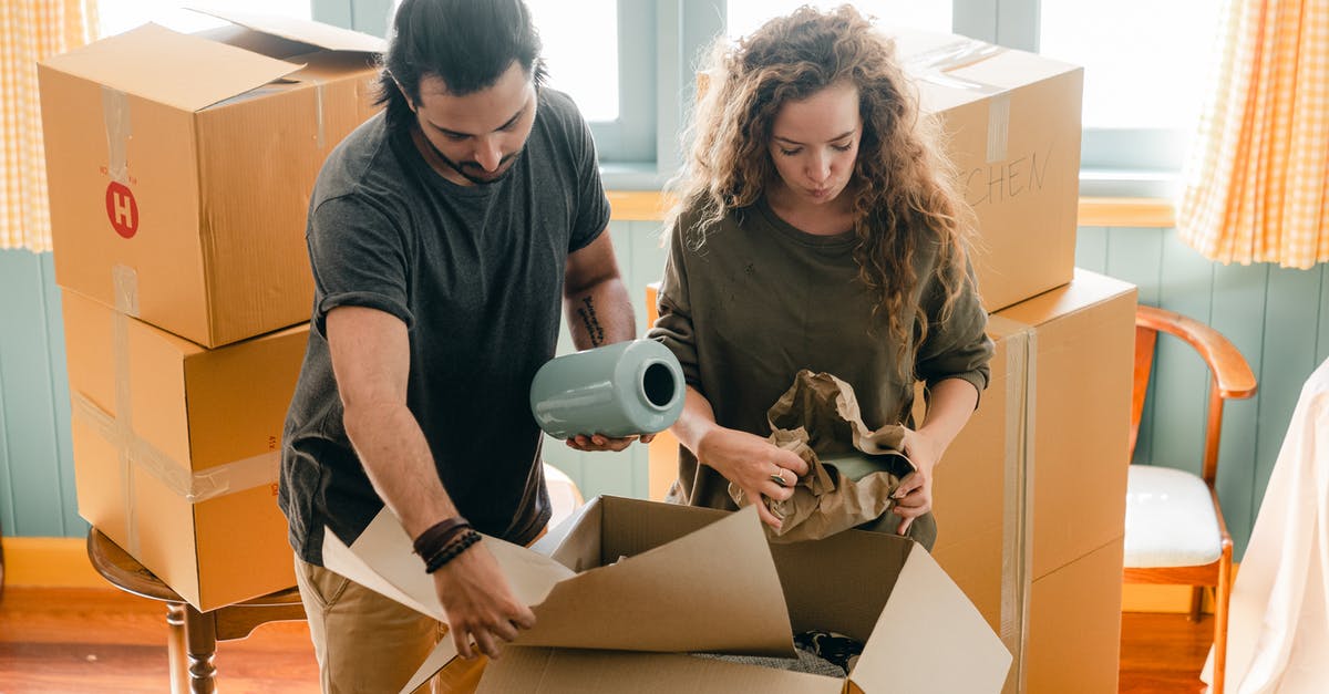 Rolling shirts in a bundle VS laying them flat while packing? - Multiethnic couple packing belongings in parchment near pile of boxes Rolling shirts in a bundle VS laying them flat while packing? - Multiethnic couple packing belongings in parchment near pile of boxes