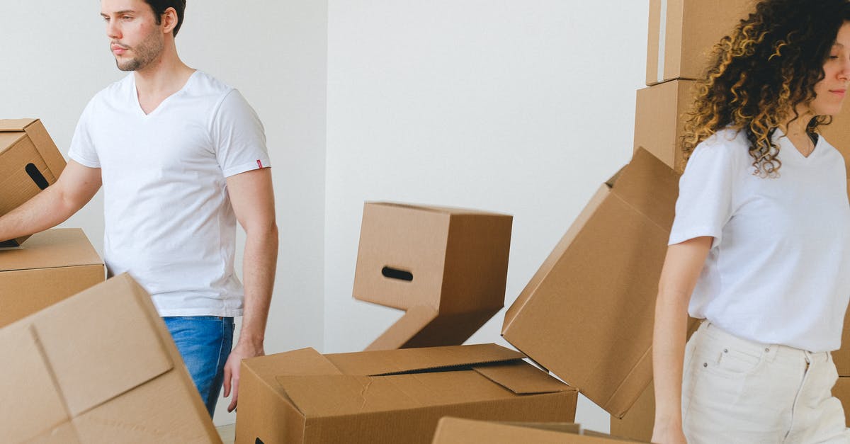 Rolling shirts in a bundle VS laying them flat while packing? - Serious young man and woman in white t shirts carrying carton boxes in light room while moving into new apartment together Rolling shirts in a bundle VS laying them flat while packing? - Serious young man and woman in white t shirts carrying carton boxes in light room while moving into new apartment together