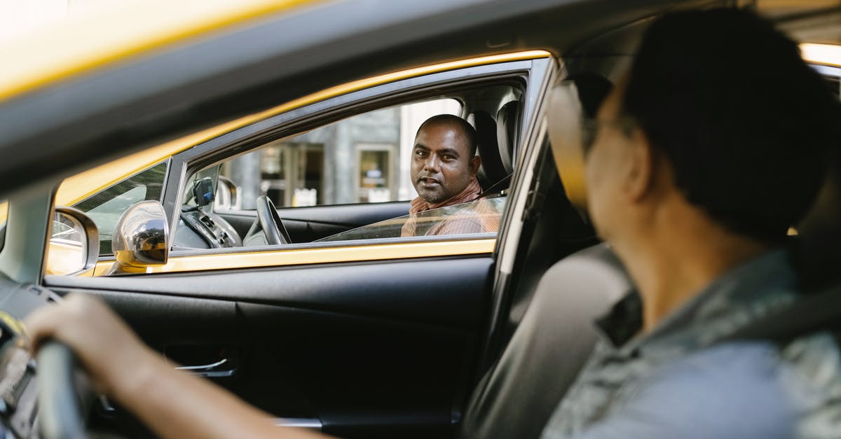 Russia, how to politely ask a taxi driver for seatbelts? - Side view of adult ethnic male cab driver interacting with anonymous colleague driving auto while looking at each other in city Russia, how to politely ask a taxi driver for seatbelts? - Side view of adult ethnic male cab driver interacting with anonymous colleague driving auto while looking at each other in city