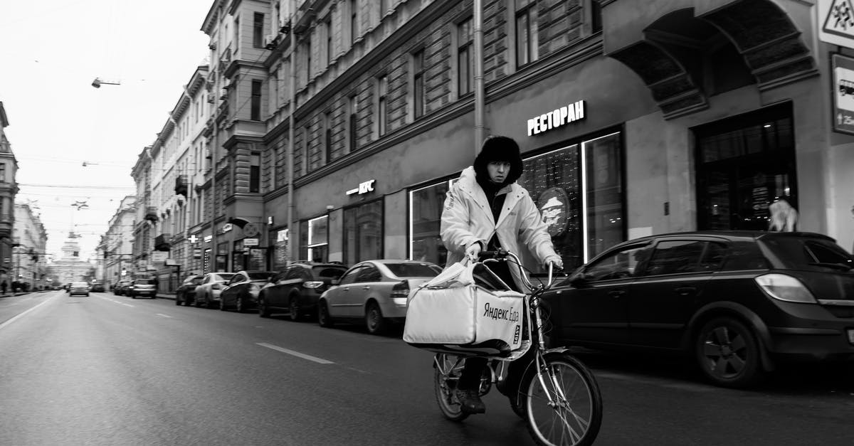 Russia visa registration when staying on the move - Man from delivery riding bicycle along urban road Russia visa registration when staying on the move - Man from delivery riding bicycle along urban road