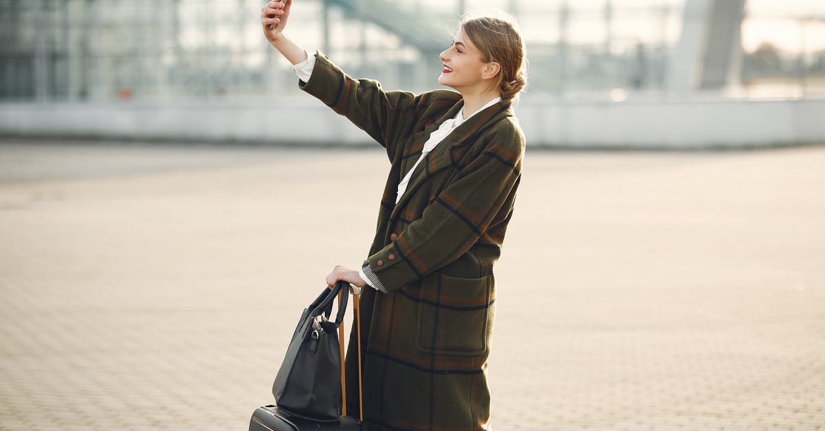 Ryanair baggage - taking more than 1 bag - Stylish young woman with luggage taking selfie outside modern glass building Ryanair baggage - taking more than 1 bag - Stylish young woman with luggage taking selfie outside modern glass building