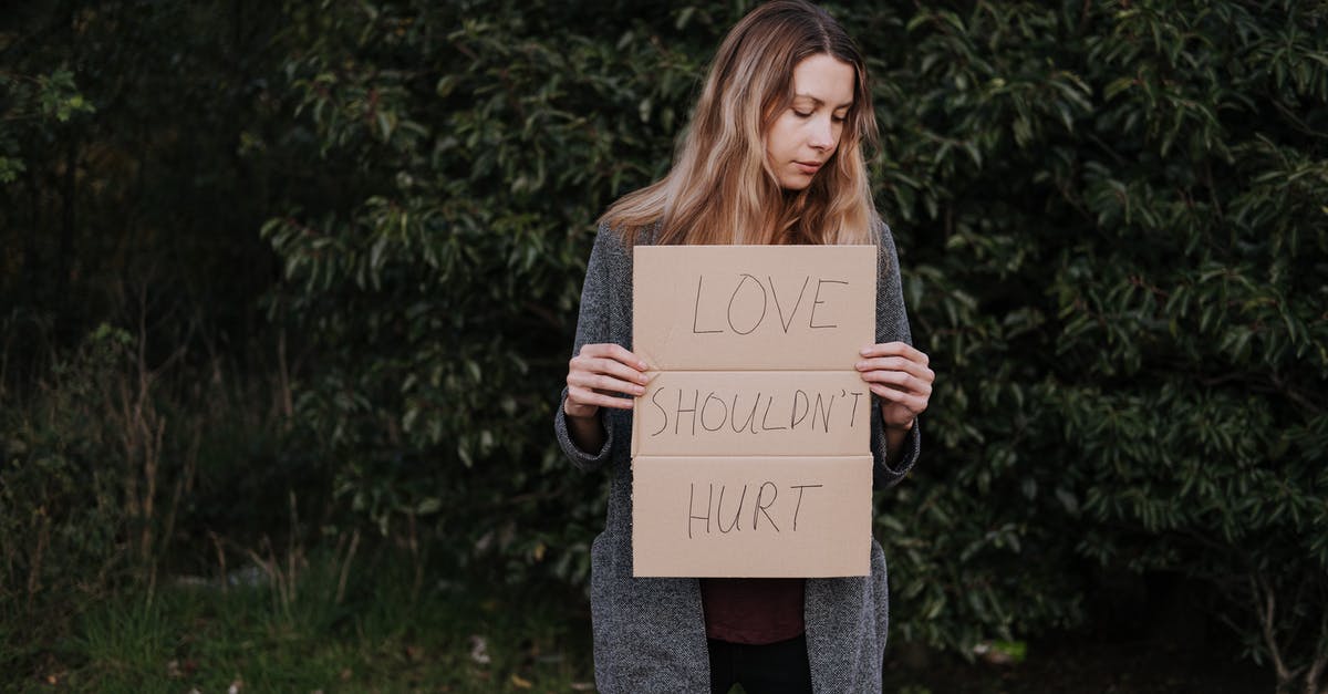 Safeguarding against extra expenditures Natural disasters during travels - Lonely upset female in casual outfit standing near trees and grass while holding cardboard against abuse with inscription Love Should Not Hurt Safeguarding against extra expenditures Natural disasters during travels - Lonely upset female in casual outfit standing near trees and grass while holding cardboard against abuse with inscription Love Should Not Hurt