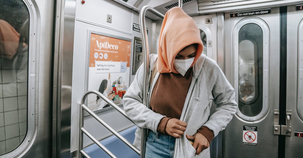Safety concerns for traveling the Leh district - Muslim female in casual clothes medical mask and traditional headscarf in subway train Safety concerns for traveling the Leh district - Muslim female in casual clothes medical mask and traditional headscarf in subway train