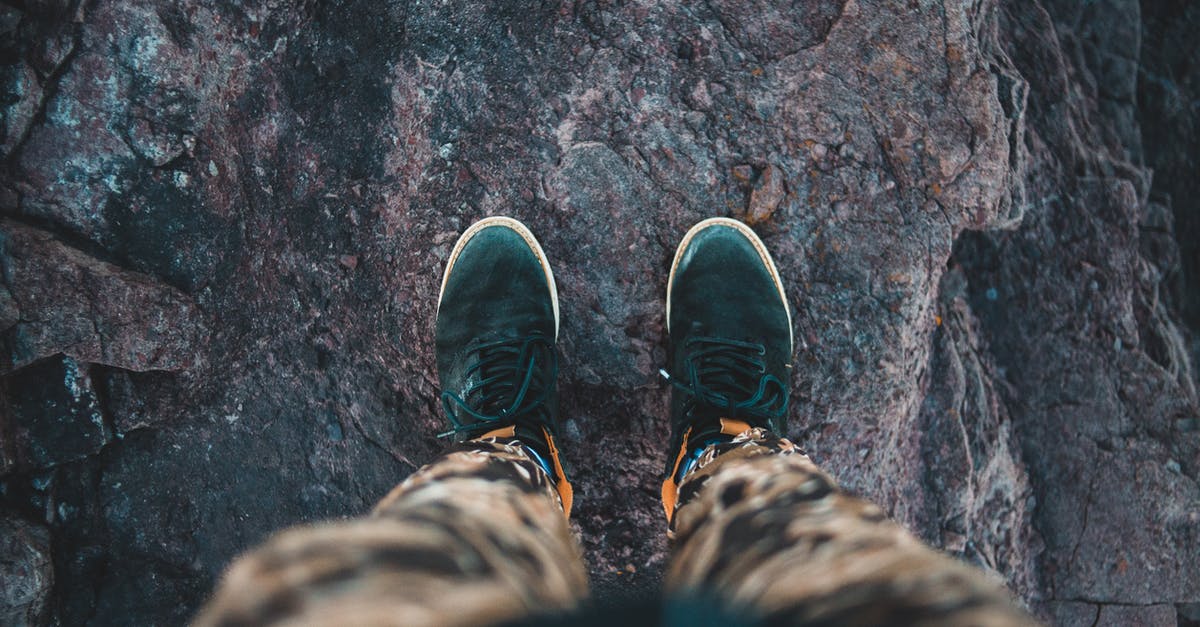 Salzburg: Eisriesenwelt, Only hiking from bottom to top [closed] - From above of crop anonymous anonymous traveler in stylish sneakers standing on top of rough rocky cliff and admiring view