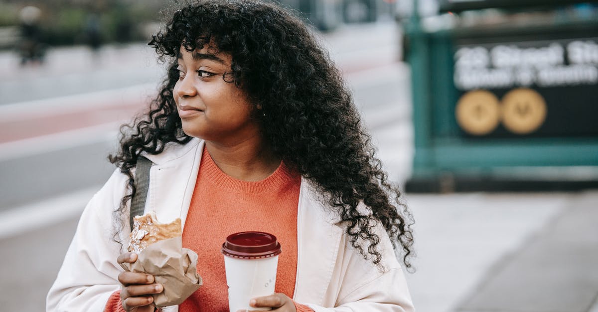 Sandwich alternatives for city trips - Glad adult African American female in casual outfit enjoying tasty sandwich and takeaway coffee while standing on city street and looking away Sandwich alternatives for city trips - Glad adult African American female in casual outfit enjoying tasty sandwich and takeaway coffee while standing on city street and looking away