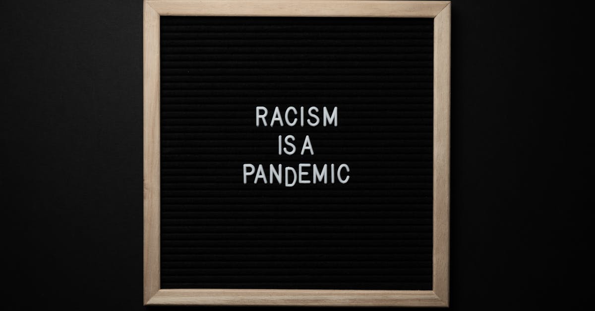 Schengen Visa . No response from the Consulate [closed] - Overhead view of slogan Racism Is Pandemic on black square signboard in light of lamps on black background