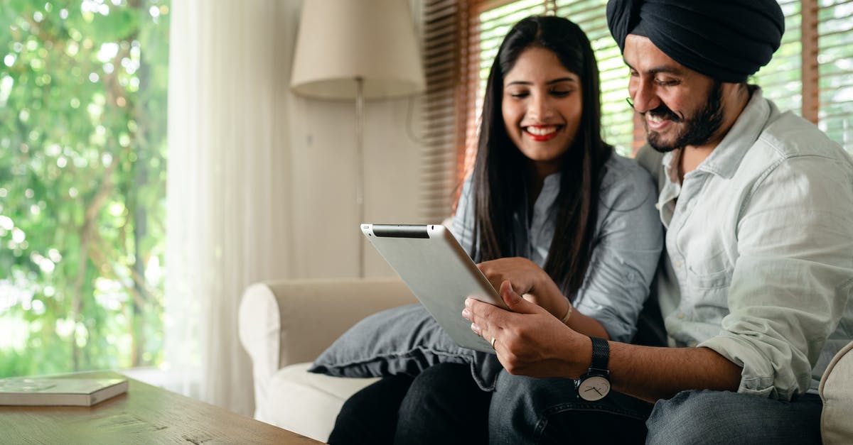 Schengen visa application by an Indian studying in the UK - Optimistic ethnic male and female in casual outfit sitting on sofa in living room in daytime and using tablet together Schengen visa application by an Indian studying in the UK - Optimistic ethnic male and female in casual outfit sitting on sofa in living room in daytime and using tablet together