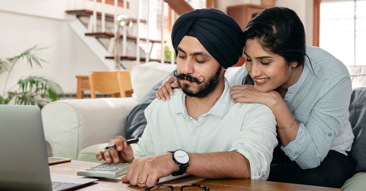 Schengen Visa for a financially dependent Indian Citizen - Cheerful ethnic couple using calculator while sitting at table Schengen Visa for a financially dependent Indian Citizen - Cheerful ethnic couple using calculator while sitting at table
