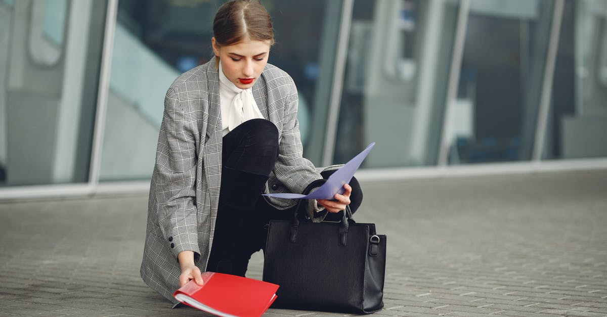 Schengen visa in almost full passport - Distracted female manager in trendy wear collecting scattered documents and passport from sidewalk into briefcase near glass wall of modern building Schengen visa in almost full passport - Distracted female manager in trendy wear collecting scattered documents and passport from sidewalk into briefcase near glass wall of modern building