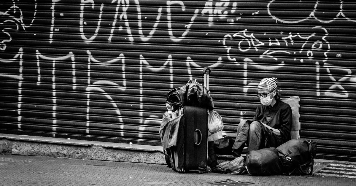Schengen visa validity period before travel - Black and white of anonymous traveler in sterile mask and eyewear sitting on road near ribbed graffiti wall and backpack during COVID 19 pandemic Schengen visa validity period before travel - Black and white of anonymous traveler in sterile mask and eyewear sitting on road near ribbed graffiti wall and backpack during COVID 19 pandemic