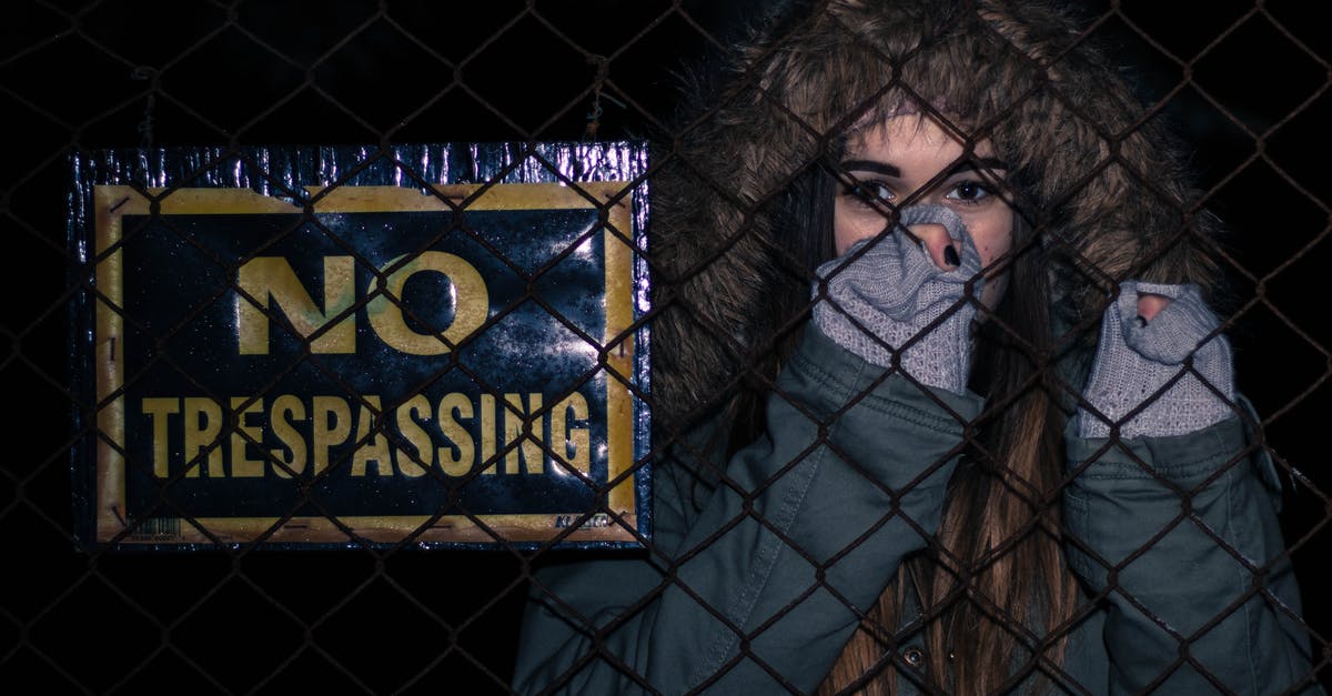 SCS Implant airport security fears [duplicate] - Woman Behind Black Chainlink Fence With No Trespassing Signage