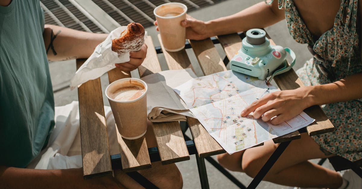 Search flights by stopping location - From above of crop anonymous couple searching route in map while having coffee and croissant Search flights by stopping location - From above of crop anonymous couple searching route in map while having coffee and croissant