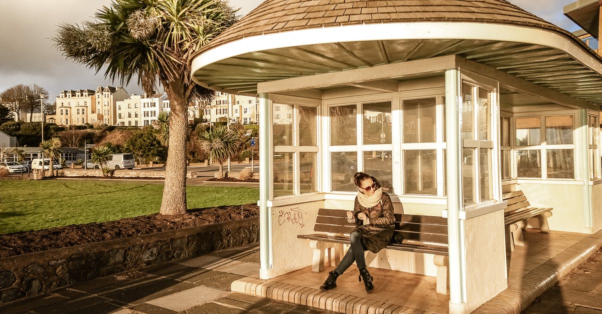 Second most photographed building in the southern hemisphere - why? - Full body young female in casual warm wear sitting on bench in white small summerhouse located in green district of southern town Second most photographed building in the southern hemisphere - why? - Full body young female in casual warm wear sitting on bench in white small summerhouse located in green district of southern town