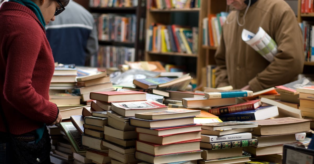 Secondhand book market or area in Beijing? - Woman and Man Standing Beside Piles of Books Secondhand book market or area in Beijing? - Woman and Man Standing Beside Piles of Books