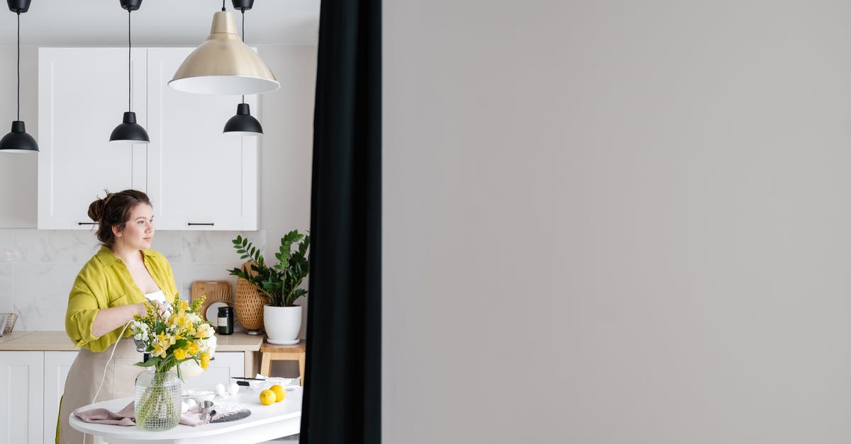 Send 1 overweight suitcase instead of 2 underweight? - Dreamy woman cooking at kitchen table in house Send 1 overweight suitcase instead of 2 underweight? - Dreamy woman cooking at kitchen table in house