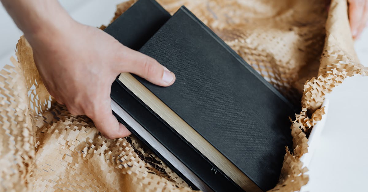 Sending a parcel from the UK to France, taxes? - Anonymous man preparing notebooks for sending by post Sending a parcel from the UK to France, taxes? - Anonymous man preparing notebooks for sending by post