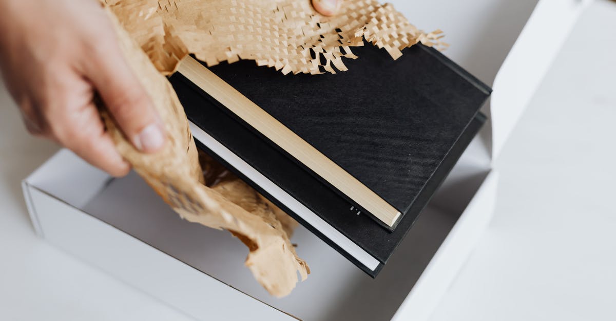 Sending a parcel from the UK to France, taxes? - Anonymous man wrapping pair of black notebooks in packing paper Sending a parcel from the UK to France, taxes? - Anonymous man wrapping pair of black notebooks in packing paper