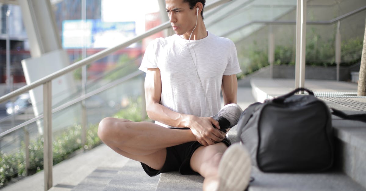 Seoul-Toronto-Montreal, skipping last leg, what happens to my luggage? - Young ethnic athlete in earbuds stretching body while sitting on stairs at entrance of contemporary building