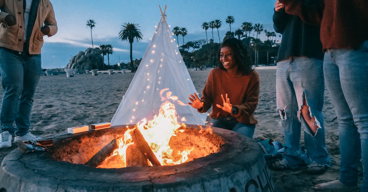 Setting up a tent on a beach in Greece - Woman Warming Her Hands in Front of the Fire Pit Setting up a tent on a beach in Greece - Woman Warming Her Hands in Front of the Fire Pit