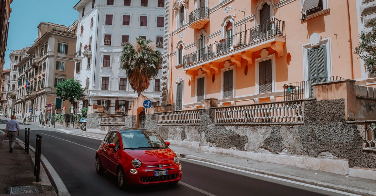Shipping my car from Egypt to Europe - Red 5-door Hatchback On A Narrow Street Lined With Apartment Buildings