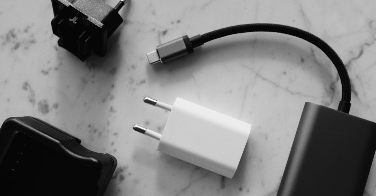Short connection on LCC at ICN - Composition of various modern charging units with adapter and small black external battery with short cable placed on white marble table Short connection on LCC at ICN - Composition of various modern charging units with adapter and small black external battery with short cable placed on white marble table