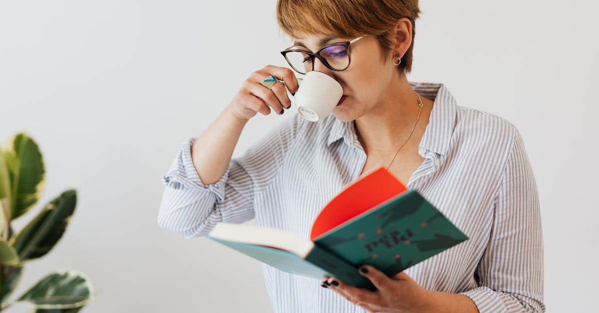 Short-term study visa UK - Crop pensive female in eyeglasses and casual wear reading interesting book in hardcover and drinking hit aromatic coffee from white ceramic cup against white wall and green plant Short-term study visa UK - Crop pensive female in eyeglasses and casual wear reading interesting book in hardcover and drinking hit aromatic coffee from white ceramic cup against white wall and green plant