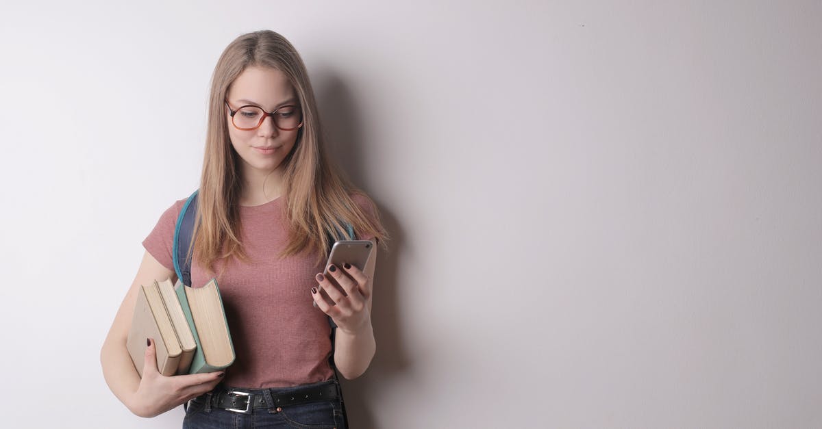 Should I book Air Berlin in advance given the ongoing take over? - Confident intelligent female student in eyeglasses wearing pink t shirt and black jeans using cellphone while taking books standing against gray wall Should I book Air Berlin in advance given the ongoing take over? - Confident intelligent female student in eyeglasses wearing pink t shirt and black jeans using cellphone while taking books standing against gray wall