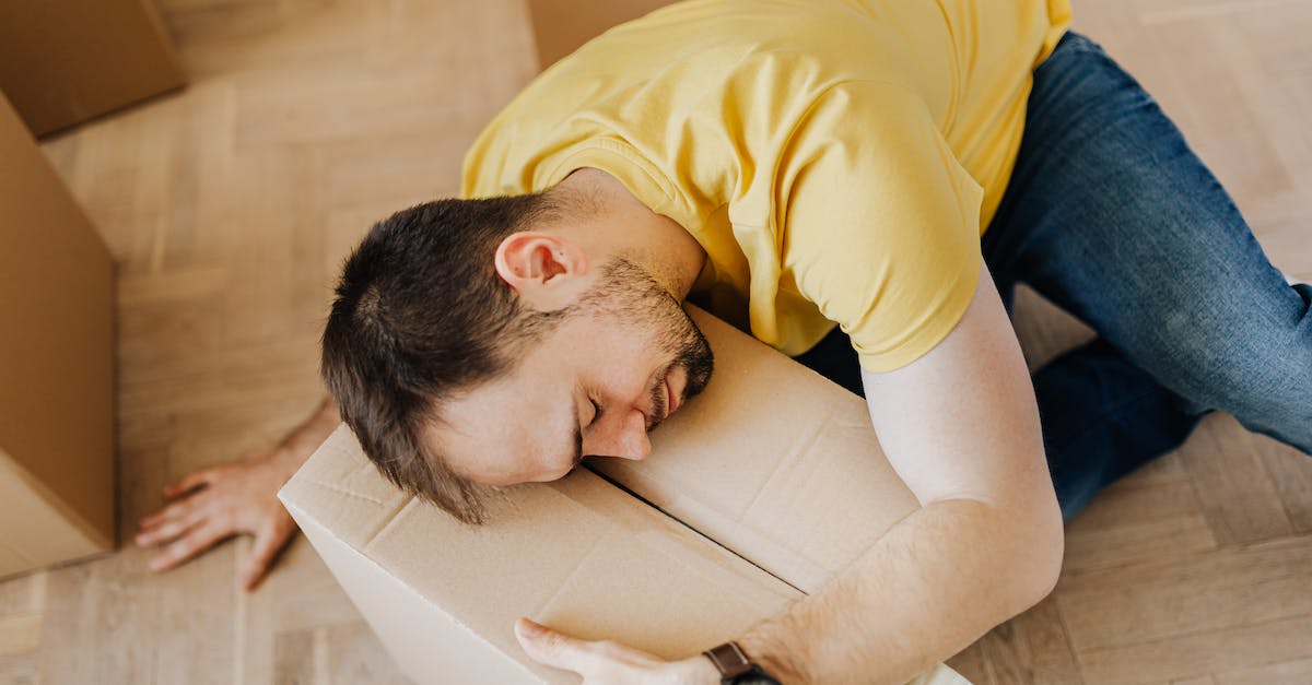 Should I buy the Suica & N'EX package to go from Narita to Tokyo? - High angle of fatigued male in casual wear sleeping on floor with cardboard box after packing belongings before moving out
