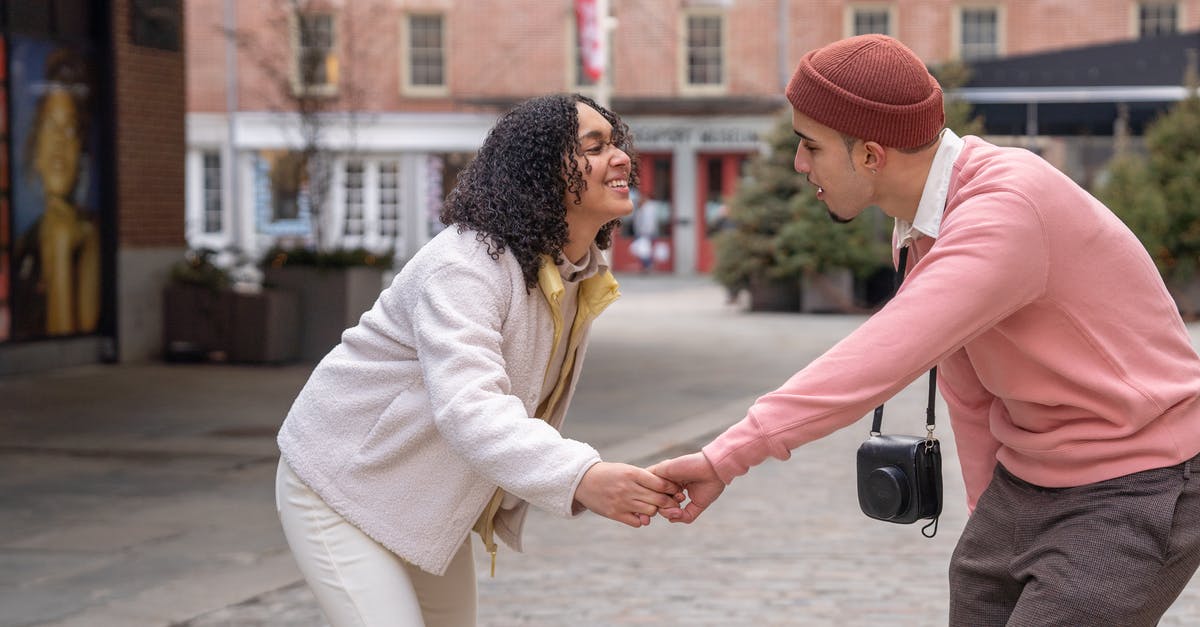 Should I insist on a refund or take Ryanair's offer to move travel date free of charge? [closed] - Side view of joyful young Hispanic couple in stylish clothes holding hands and dancing on city square during romantic date