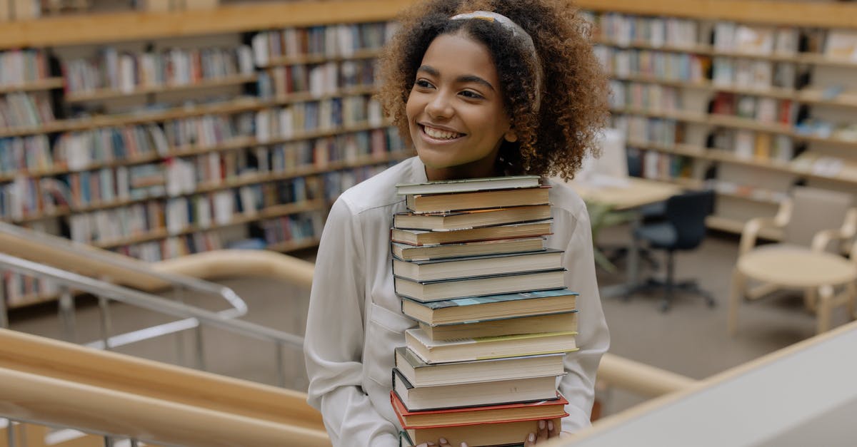 Should I put books in carry-on or checked luggage? - Photo Of Woman Carrying Stack Of Books Should I put books in carry-on or checked luggage? - Photo Of Woman Carrying Stack Of Books
